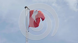 Swiss flag on pole, white cross on red background in slow motion.