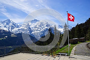 Swiss flag with snow capped mountains behind