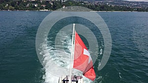 Swiss flag waving on the back of speed boat leaving Lausanne port on Lake Leman Geneva Lake, Switzerland