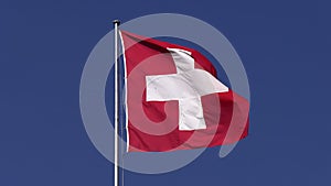 Swiss flag waving in the wind on a building roof, blue sky