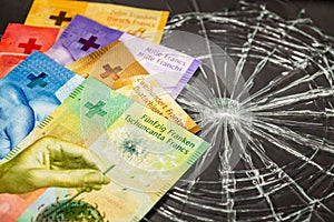 Swiss francs lying on broken glass, financial concept, Weakening of the Swiss currency