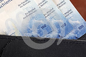 Swiss francs notes stick out of the small wallet