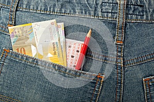 Swiss money and lottery bet slip in pocket