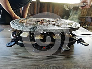 Swiss raclette. A table filled with meat. Raclette machine with a surface for frying and marble plate. Swiss raclette or the Dutch