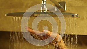 Switch on the water in the shower head. Man's hand under the water drops