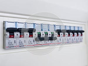 Switches in electrical fuse box. Many black circuit breakers in a row in position ON and three switch in position OFF. Power contr