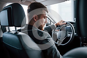 Switching gears. Modern businessman trying his new car in the automobile salon