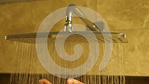 Switching on the shower head in the bathroom, the flow of water and falling drops in slow motion handheld footage. Close