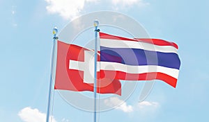 Switzerland and Thailand, two flags waving against blue sky