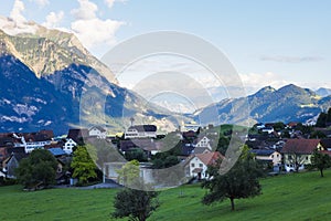 Switzerland with view of houses on green grassy hills, majestic mountains in background