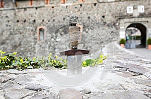 Sword in the stone near the castle. Saint Arthur`s style medieval period. Middle ages photo. Old walls and weapon. Ancient histor