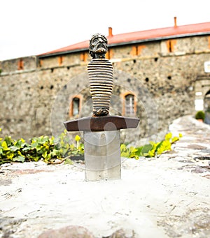 Sword in the stone near the castle. Saint Arthur`s style medieval period. Middle ages photo. Old walls and weapon. Ancient histor