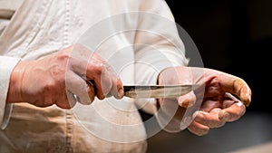 Swordsmith is checking sharpness of blade of small katana