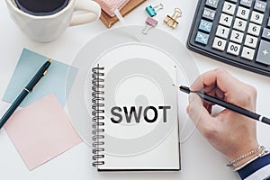 SWOT text written on notepad on the office background