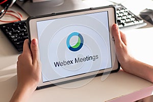 Hands holding a tablet with Webex cloud meetings application