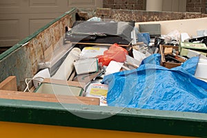 Skip bin full of household waste rubbish on the front yard. House clean up concept