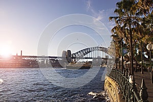 Sydney Harbour Bridge with golden sun flare on calm seas