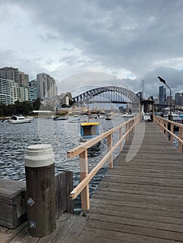 Sydney\'s harbour foreshore set against the famous Sydney Harbour bridge on a cloudy overcast day photo