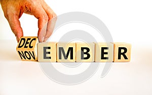 Symbol for the change from November to December, winter. Businessman turns wooden cubes, changes the concept word November to