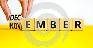 Symbol for the change from November to December, winter. Businessman turns wooden cubes, changes the concept word November to