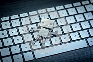 Symbol for a chatbot or social bot. Toy robot lying on a computer keyboard