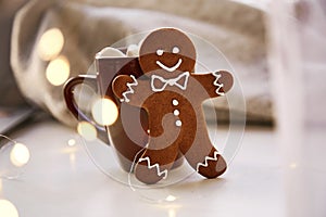 Symbol of Christmas - homemade gingerbread cookie and blurred bokeh decor. Festive Christmas decorations with hot drink