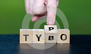 Symbol for correcting a typo. Hand turns dice and corrects the expression tybo to typo photo