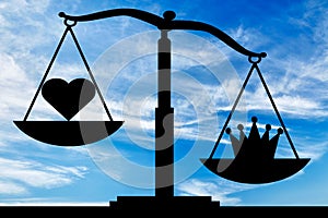 Symbol crown selfishness in priority over the symbol of the heart altruism on the scales