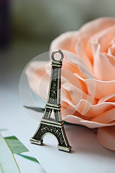 Miniature Eiffel tower in silver on the background of a blooming pink rose