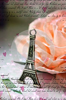 Miniature Eiffel tower in silver on the background of a blooming pink rose