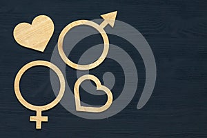 A symbol of gender equality made of plywood. Black wooden background. Male and female symbols