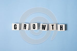 Symbol of growth. a wooden cube and changes words growth. Beautiful blue and white background, copy space. Business and
