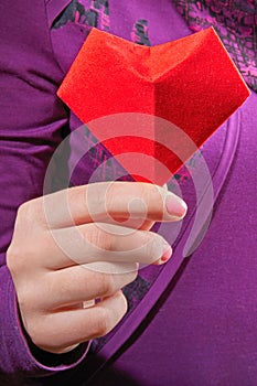 Symbol of the heart in women's palms. Red paper heart in woman hands. Close-up.