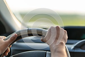 Symbol image. Hands on the steering wheel of a car