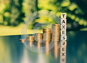 Symbol for increasing taxes. Dice form the word taxes next to increasing high stacks of coins