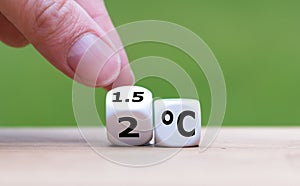 Symbol for limiting global warming. Hand turns a dice and changes the expression `2Â°C` to `1.5Â°C`, or vice versa.