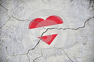 The symbol of the national flag of Austria in the form of a heart on a cracked concrete wall