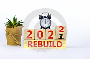 Symbol of planning 2022 rebuild new year. Alarm clock. Turned a wooden cube, changed words `rebuild 2021` to `rebuild 2022`.