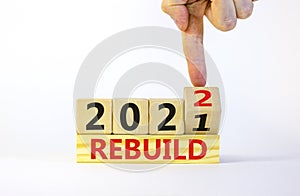 Symbol of planning 2022 rebuild new year. Businessman turns a wooden cube and changes words `rebuild 2021` to `rebuild 2022`.