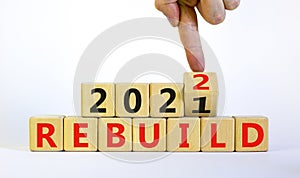 Symbol of planning 2022 rebuild new year. Businessman turns a wooden cube and changes words `rebuild 2021` to `rebuild 2022`.