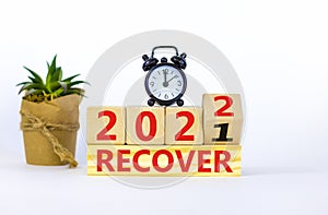 Symbol of planning 2022 recover new year. Alarm clock. Turned a wooden cube, changed words `recover 2021` to `recover 2022`.