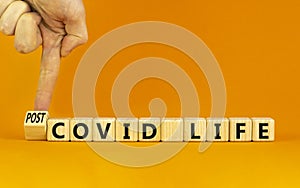 Symbol for a post-covid life. Businessman turns a cube and changes words `covid life` to `post-covid life`. Beautiful orange