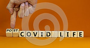 Symbol for a post-covid life. Businessman turns cubes and changes words `covid life` to `post-covid life`. Beautiful orange