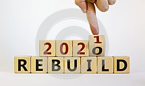 Symbol of 2021 rebuild. Male hand flips wooden cubes and changes the inscription `Rebuild 2020` to `Rebuild 2021`. Beautiful w