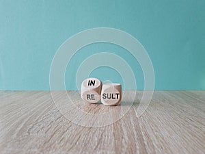 Symbol that a result is an insult. Dice form the words result and insult. Beautiful blue background, wooden table. Business photo
