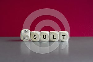 Symbol that a result is an insult. Turned a cube and changes the word result and insult. Beautiful red background, grey table. photo