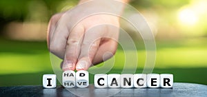 Symbol for a succesful cancer treatment. Hand turns dice and changes the expression `I have cancer` to `I had cancer`.