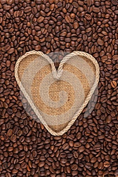 Symbolic heart made of rope lies on sackcloth and coffee beans