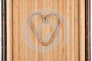 Symbolic heart made of rope lying on a furled bamboo mat
