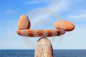 Symbolic scales of the stones, illuminated by the evening sun, against the sea, close-up. Pros and cons concept